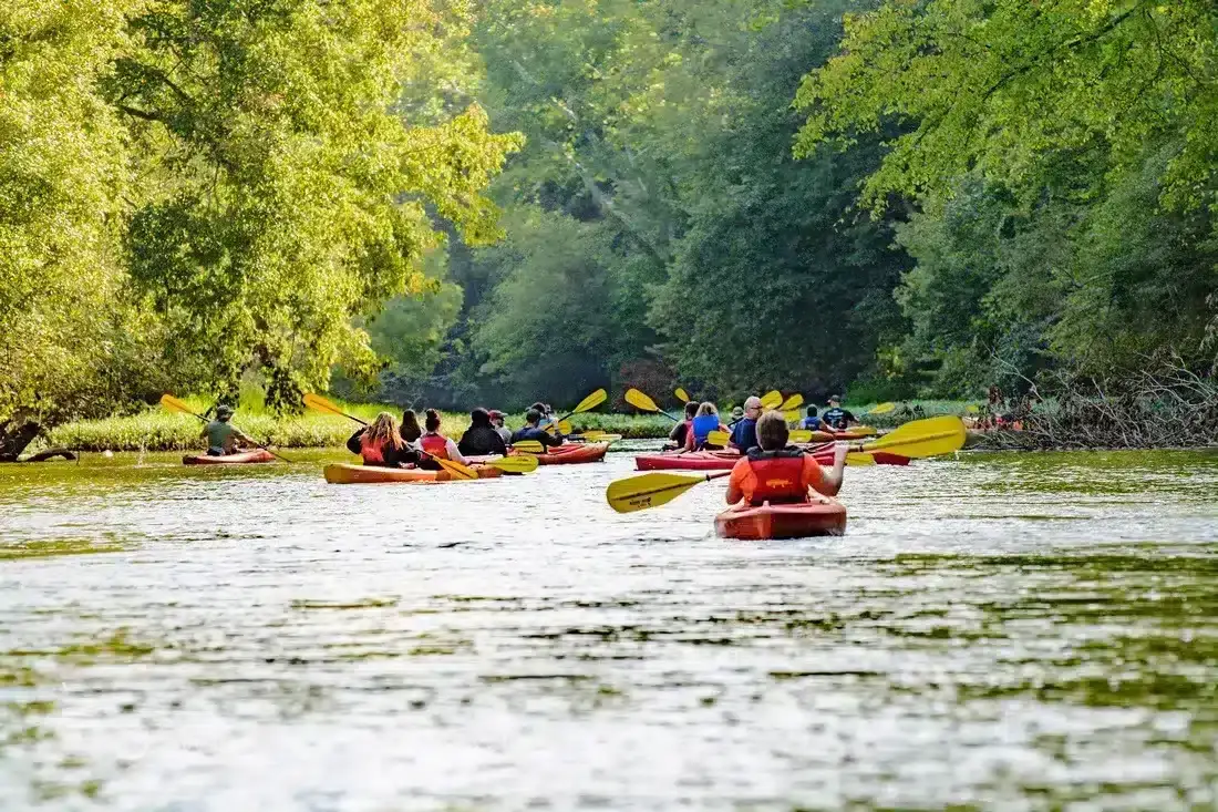 Paddlers in single kayaks on a calm stretch of the Hocking River in Hocking Hills, Ohio